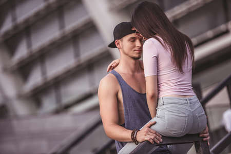 Stylish young couple is hugging and smiling while walking in the cityの写真素材