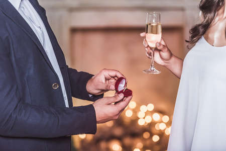 Merry Christmas and Happy New Year! Cropped image of man holding a wedding ring while making a proposal to his beautiful girlfriendの写真素材