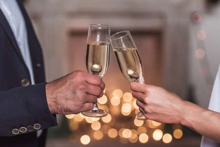 Merry Christmas and Happy New Year! Cropped image of elegant couple clinking glasses of champagne together while celebratingの写真素材