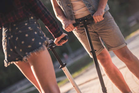Cropped image of young couple riding scooter in the parkの写真素材