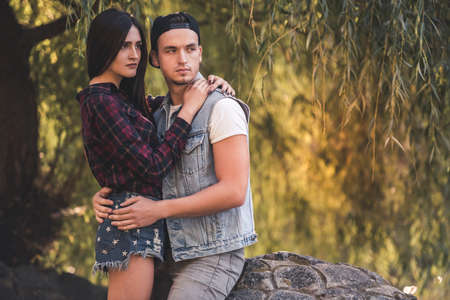 Stylish young couple is hugging while resting in the parkの写真素材