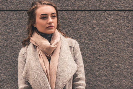 Beautiful pensive girl in coat is walking in the cityの写真素材