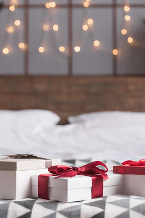 Happy holiday! Christmas presents on bed are waiting to be given. Gift boxes with ribbonsの写真素材