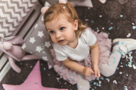 Cute little girl is playing with confetti in the children's room