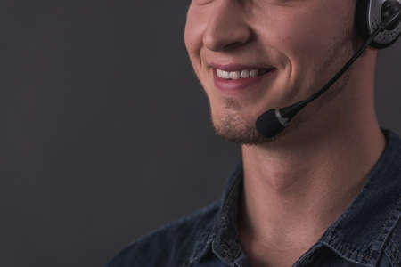 Cropped image of handsome young man in headset smiling, on gray backgroundの写真素材