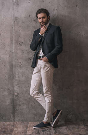 Full length portrait of handsome confident businessman with bristle, in suit, posing at camera, on gray backgroundの写真素材