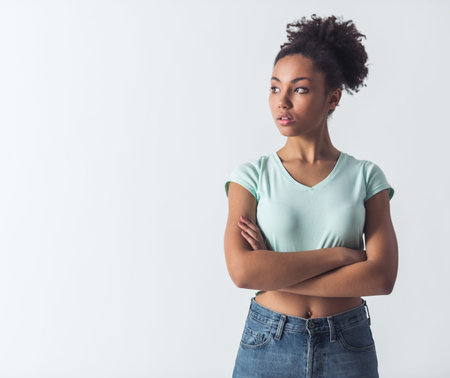 Pensive Afro-American girl in casual clothes is looking away and thinking, isolated on whiteの写真素材