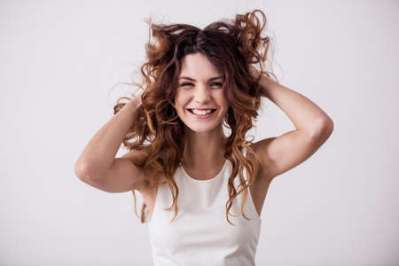 Young pretty girl on a white background playing with her hair. Shooting in the studio.の写真素材