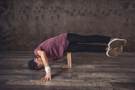 Young man break dancing on the wall background, performing tricks