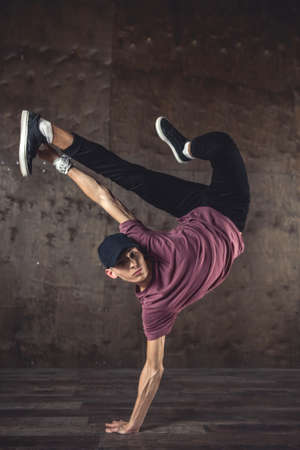 Young man break dancing on the wall background, performing tricksの写真素材
