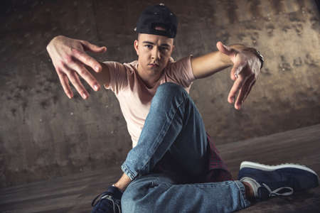 Young man break dancing on the wall background, performing tricksの写真素材