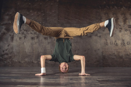 Young man break dancing on the wall background, performing tricks