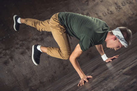 Young man break dancing on the wall background, performing tricksの写真素材