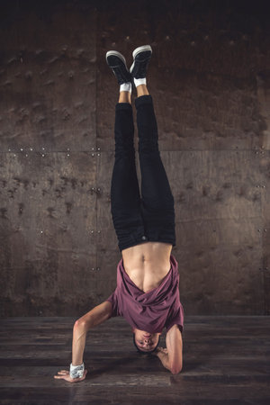 Young man break dancing on the wall background, performing tricks