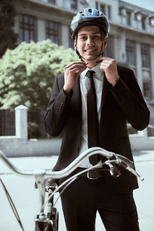 Portrait of young businessman riding bicycle to work on urban street.の写真素材