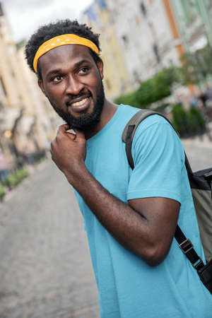 A young black man laughs while walking the streets of the bridge with a backpackの写真素材