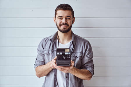 Young emotional man while shooting with old camera on light backgroundの写真素材