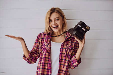 Young emotional girl while shooting with old camera on light backgroundの写真素材