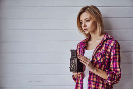 Young emotional girl while shooting with old camera on light backgroundの写真素材