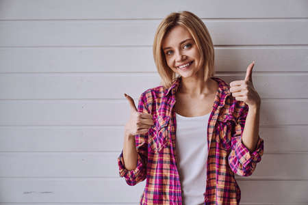 Portrait of young cheerful emotional beautiful blonde girl on light backgroundの写真素材