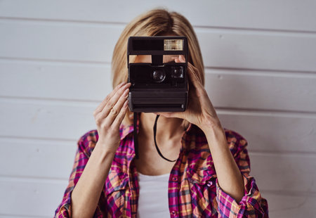 Young emotional girl while shooting with old camera on light backgroundの写真素材
