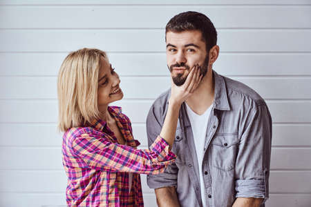 Portrait of young cheerful loving couple smiling looking at camera and hugging each other on light backgroundの写真素材