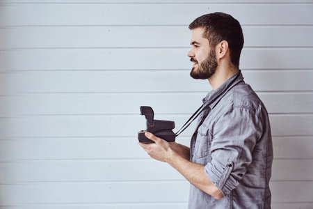 Young emotional man while shooting with old camera on light backgroundの写真素材