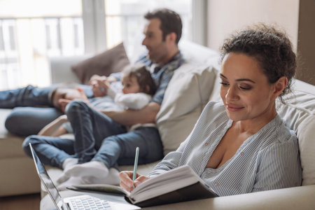Young successful freelancer woman working at home sitting on sofa against the background of her...