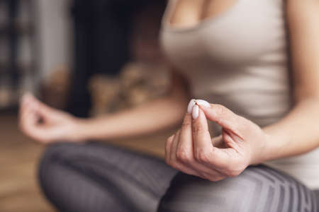 Young beautiful fitness woman at home sitting in lotus position on mat during yoga class in living room at home. Close-up on hands.の写真素材