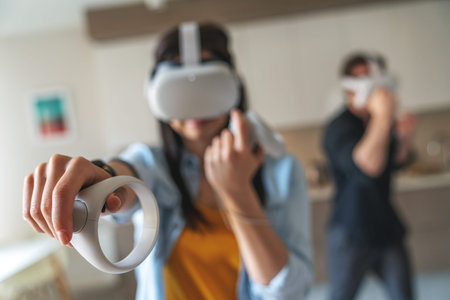 Young cheerful couple guy and girl while playing in virtual reality goggles with controllers in...