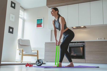 Young beautiful girl during sports at home in the apartment on the background of the kitchen.