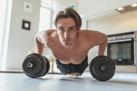 Young man during sports at home in the apartment on the background of the kitchen.
