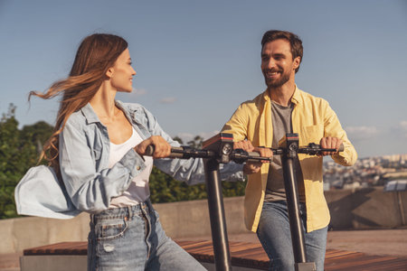 Young couple having fun talking on a bench and taking a selfie using the phone while walking in the morning city.の写真素材