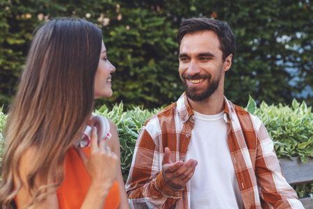 Young happy couple having fun talking while sitting on a bench while walking in the park.