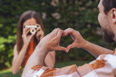 Young cheerful couple sitting on a blanket in the park during a picnic and drinking alcohol from a bottle.の写真素材