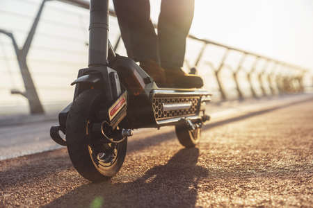 Young smiling bearded businessman in a business suit while riding an electric scooter on the background of the morning cityの写真素材
