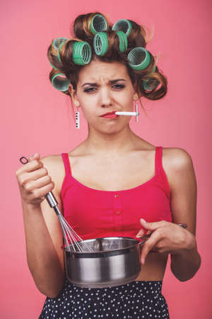 Cooking with pleasure. Happy young housewife whisking something in a panの写真素材