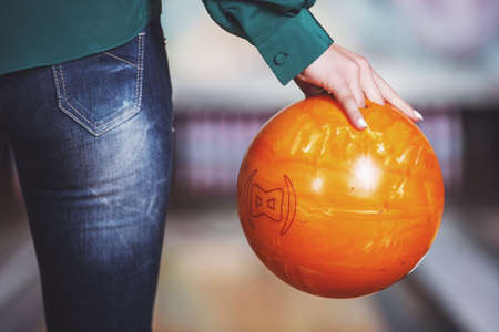 Close-up hand of young woman is holding ball against bowling alley.の写真素材
