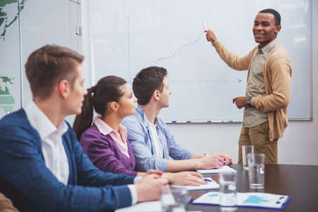 Confident international businessman in meeting at office with team.の写真素材