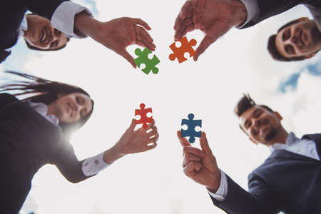 Closeup of business people wanting to put four pieces of puzzle together. Team work.の写真素材