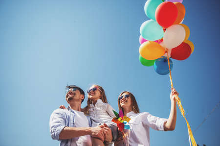 Happy family playing with balloons at the day time. Friendly family concept. Sky background.の写真素材