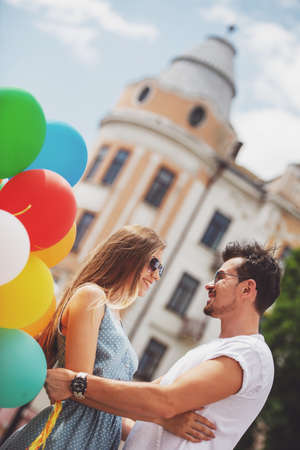 Lovely young couple with colorful balloons looking to each other and smiling.の写真素材