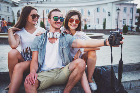 Friendship, leisure and people concept. Young people are taking selfie photo with photo camera, outdoors, in the town.の写真素材