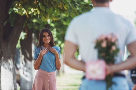 Loving young couple on a date with flowers and with a gift in the parkの写真素材