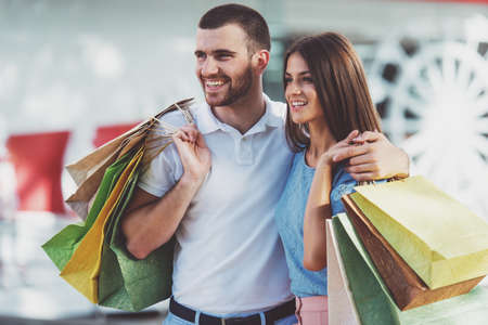 Loving young couple with bags for shopping, walk to townの写真素材