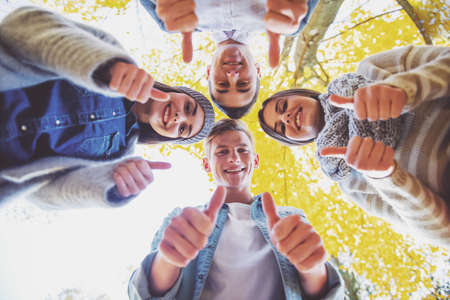 Group of young people students while walking autumn parkの写真素材
