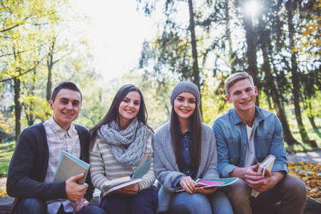 Group of young people students while walking autumn parkの写真素材