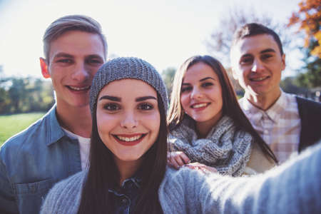 Group of young people students while walking autumn parkの写真素材