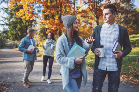 Group of young people students while walking autumn parkの写真素材