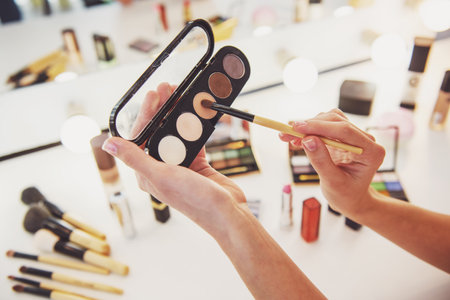 Cropped image of beautiful young woman holding eyeshadow while doing makeupの写真素材
